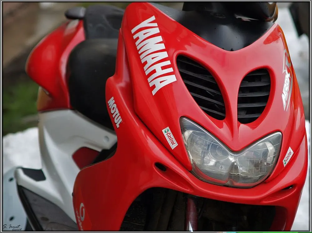 Close-up of a red scooter's headlight